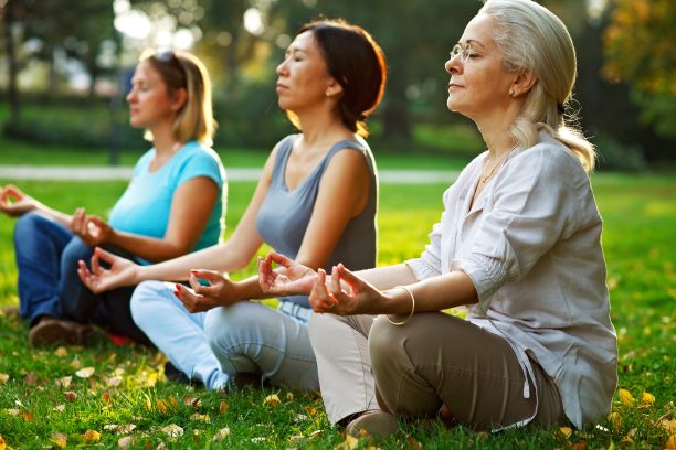 Three_women_meditating_in_park.jpg